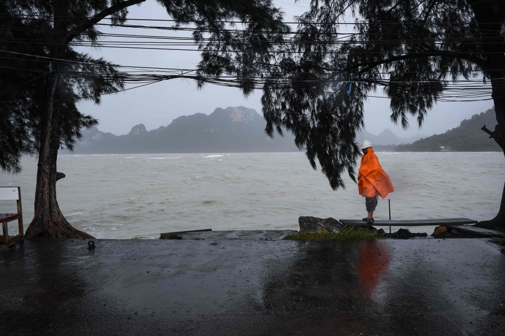 A man guards an empty pier after tour operators were forced to suspend boats to tourist islands due to tropical storm Pabuk, in the southern Thai province of Surat Thani on January 4, 2019. AFP / Lillian SUWANRUMPHA
