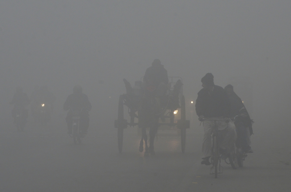 Pakistani commutes drive their vehicles on a road amid heavy fog and smog conditions in Lahore on January 3, 2019.  AFP / ARIF ALI