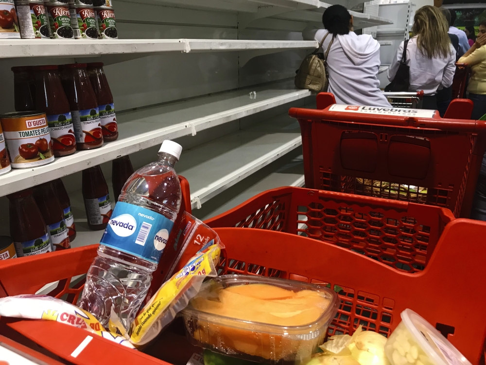 A group of people stand in line to pay at the checkout in a supermarket in Caracas, Venezuela on December 31, 2018. / YURI CORTEZ / AFP