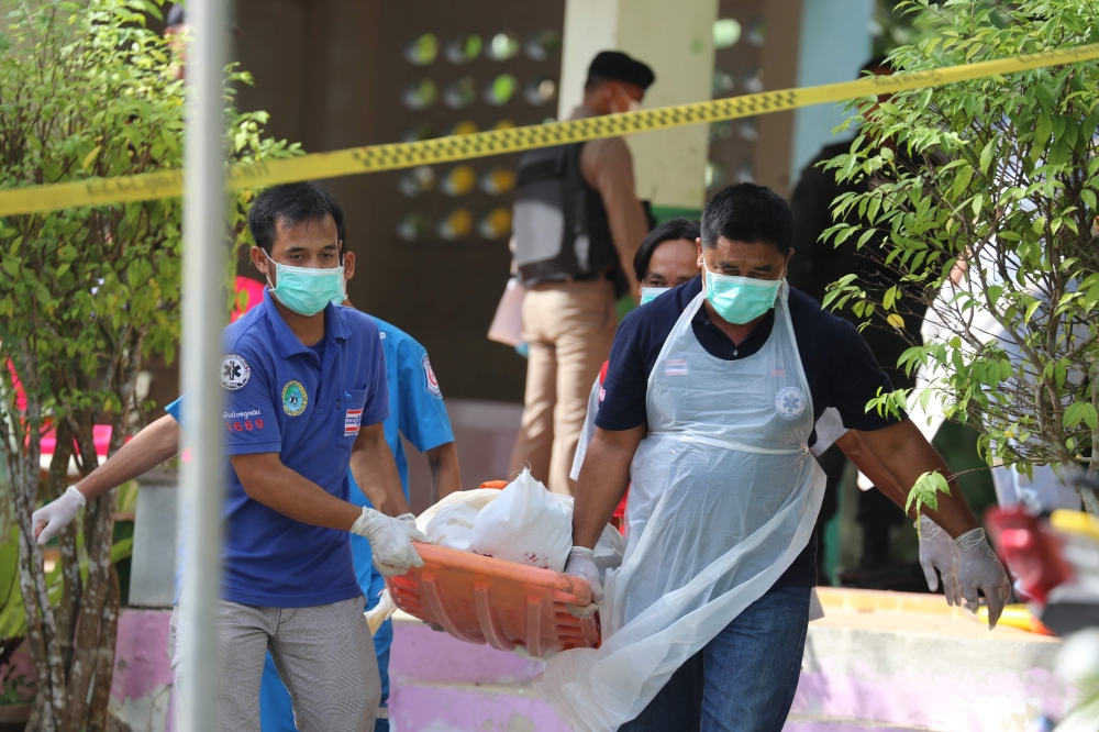 Paramedics take away a body after four Thai civil defence volunteers were shot and killed outside of a school in the restive southern province of Pattani on January 10, 2019. AFP / Tuwaedaniya Meringing 