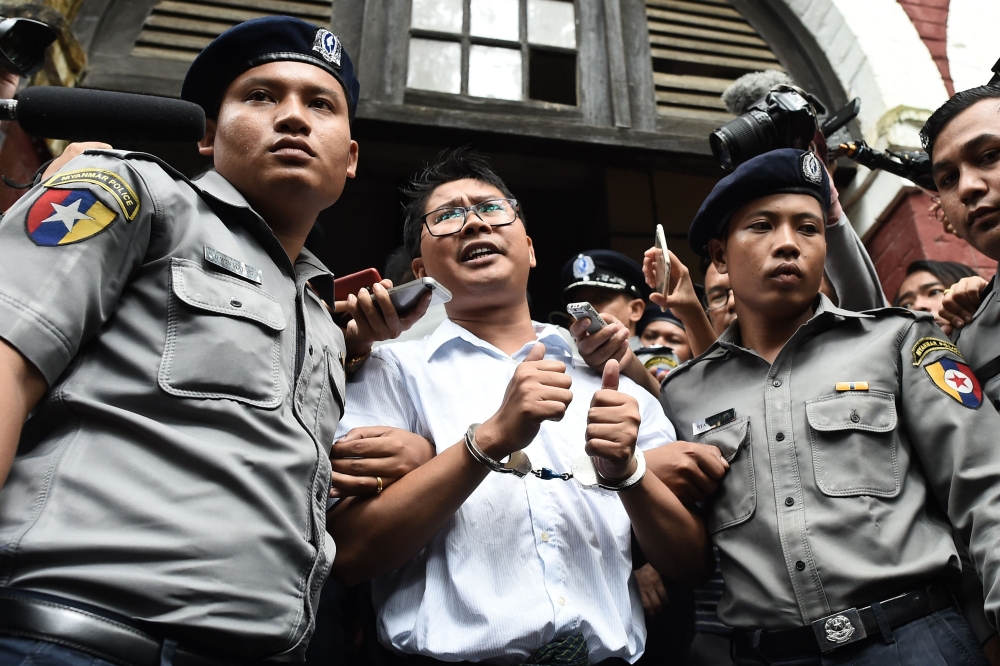 This file photo taken on September 03, 2018 shows Myanmar journalist Wa Lone (C) is escorted by police after being sentenced by a court to jail in Yangon. / AFP / Ye Aung THU 