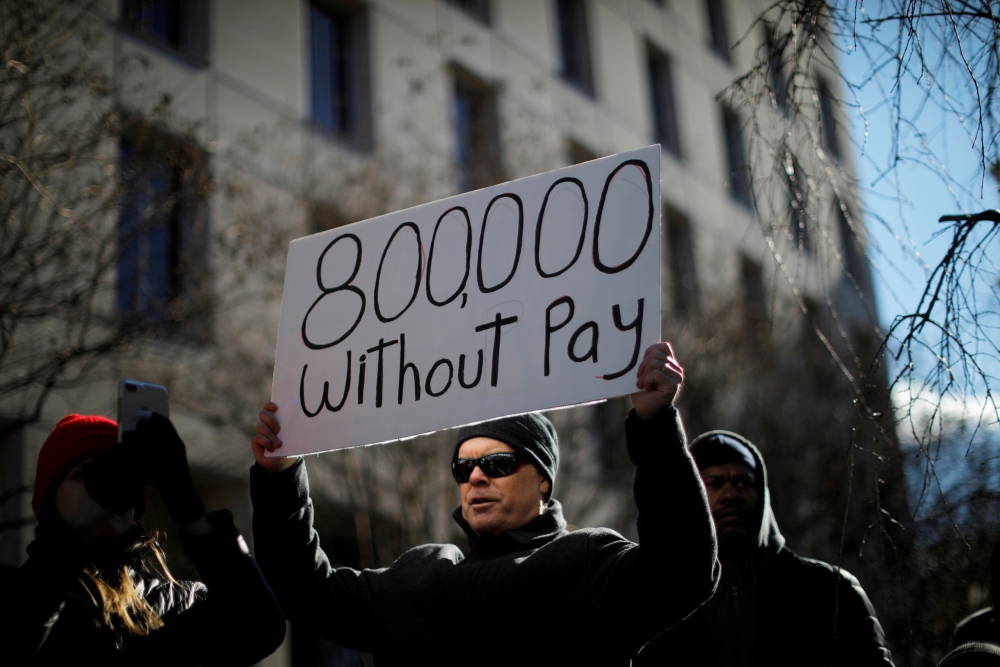 Filephoto: A demonstrator holds a sign, signifying hundreds of thousands of federal employees who won’t be receiving their paychecks as a result of the partial government shutdown, during a 