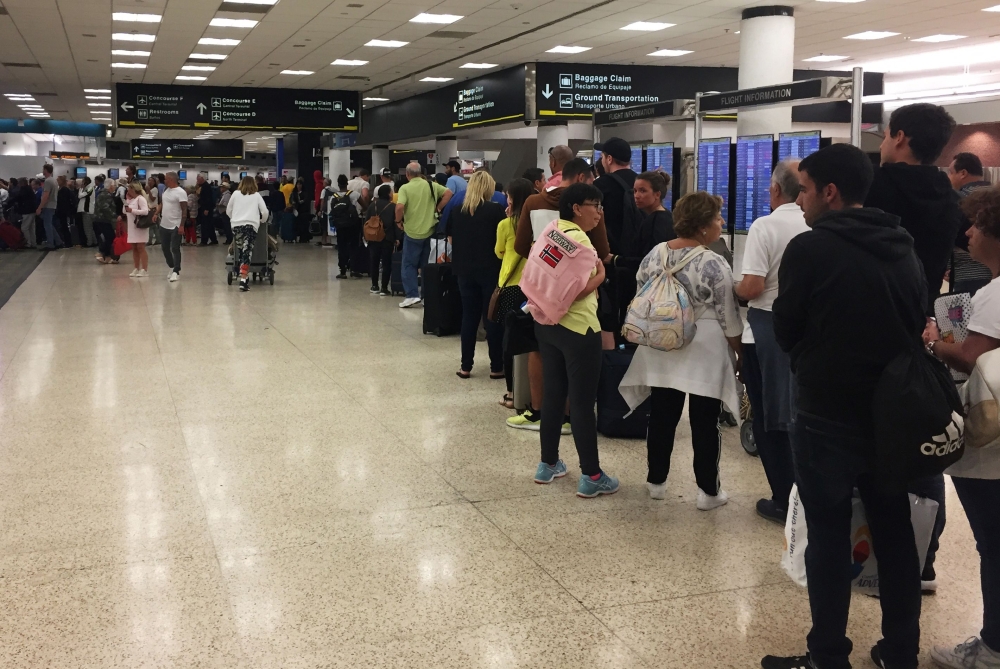 Passengers flying from Miami International Airport wait in line to enter the checkpoint at Concourse F, where some of the flights of a closed terminal were diverted, in Miami, Florida, on January 13, 2019. AFP / Leila MACOR