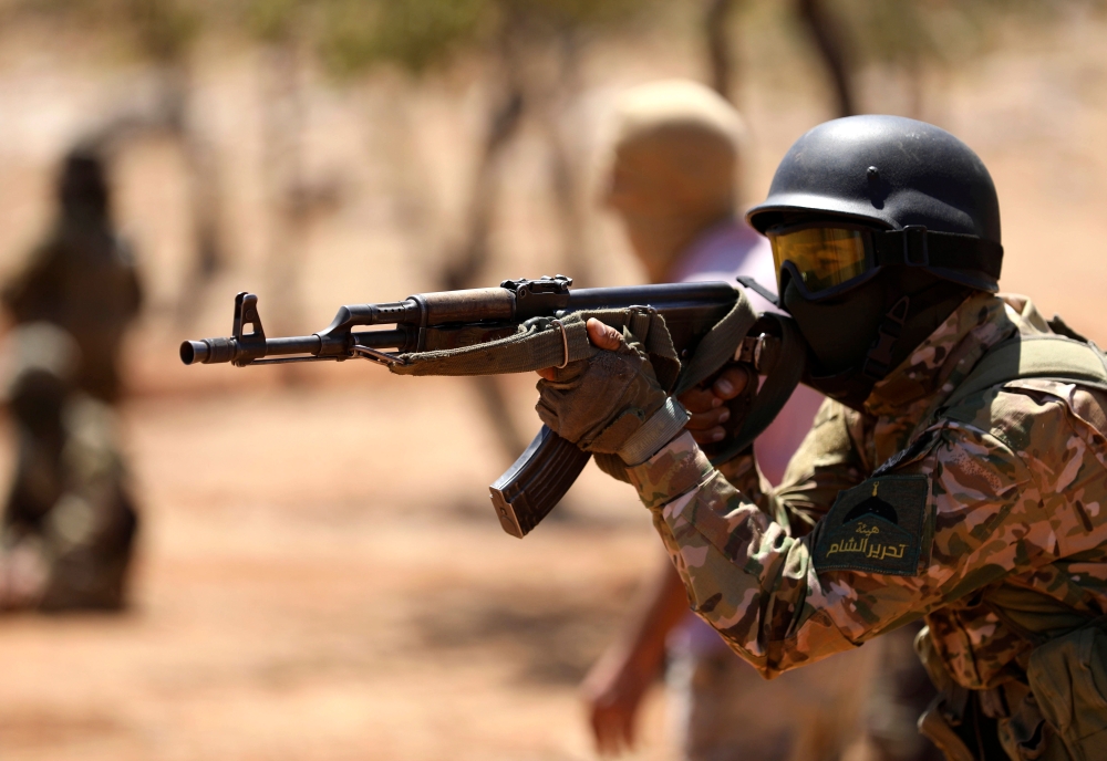 In this file photo taken on August 14, 2018 Syrian fighters attend a mock battle in anticipation of an attack by the regime on Idlib province and the surrounding countryside, during a graduation of new Hayat Tahrir al-Sham (HTS) members at a camp in the c
