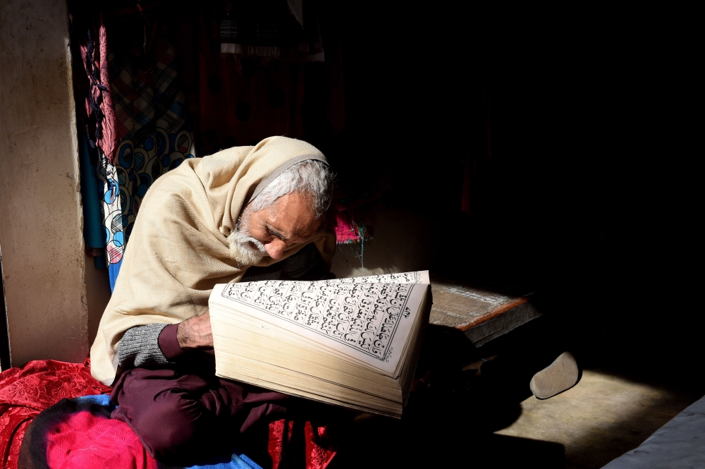 A Pakistani vendor of women garments reads the Quran while waiting for customers at his shop in Lahore on January 15, 2019. AFP / Arif Ali 





