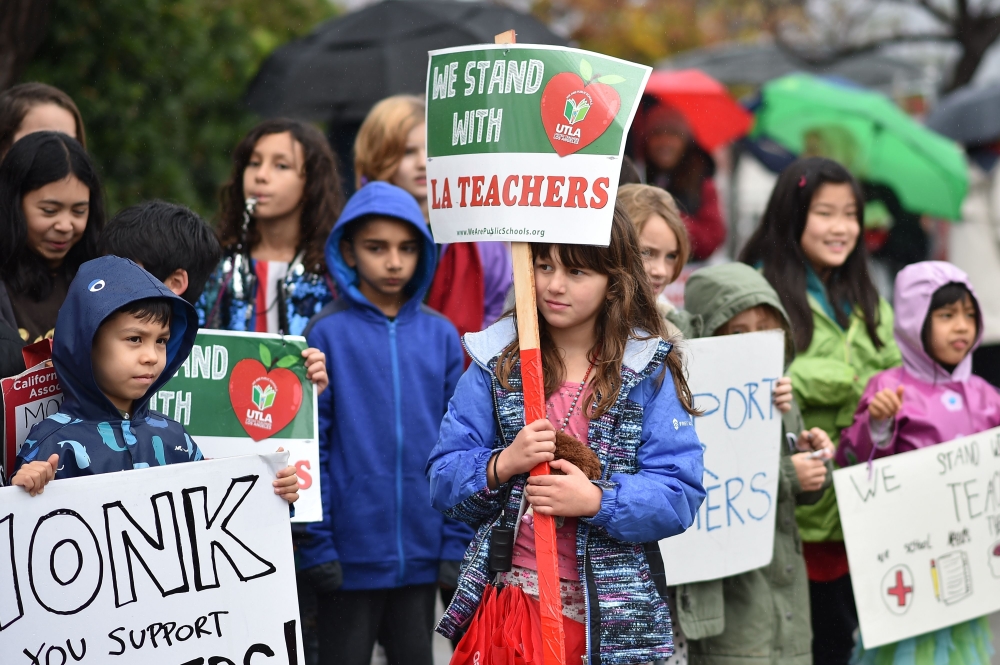 Students pose for a snapshot after walking the picket line with their teachers and parents on the third day of the teachers' strike, January 16, 2019, outside Dahlia Heights Elementary School in the Eagle Rock section of Los Angeles, California. AFP / Rob