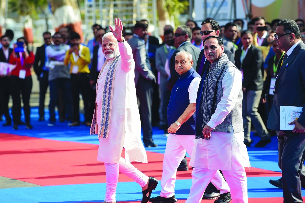 Indian Prime Minister Narendra Modi (L) waves as Gujarat state Chief Minister Vijaybhai Rupani (3L) and Deputy Chief Minister of Gujarat state Nitinbhai Patel (2L) look on at the Prime Minister's arrival, ahead of the inauguration of Vibrant Gujarat Summi