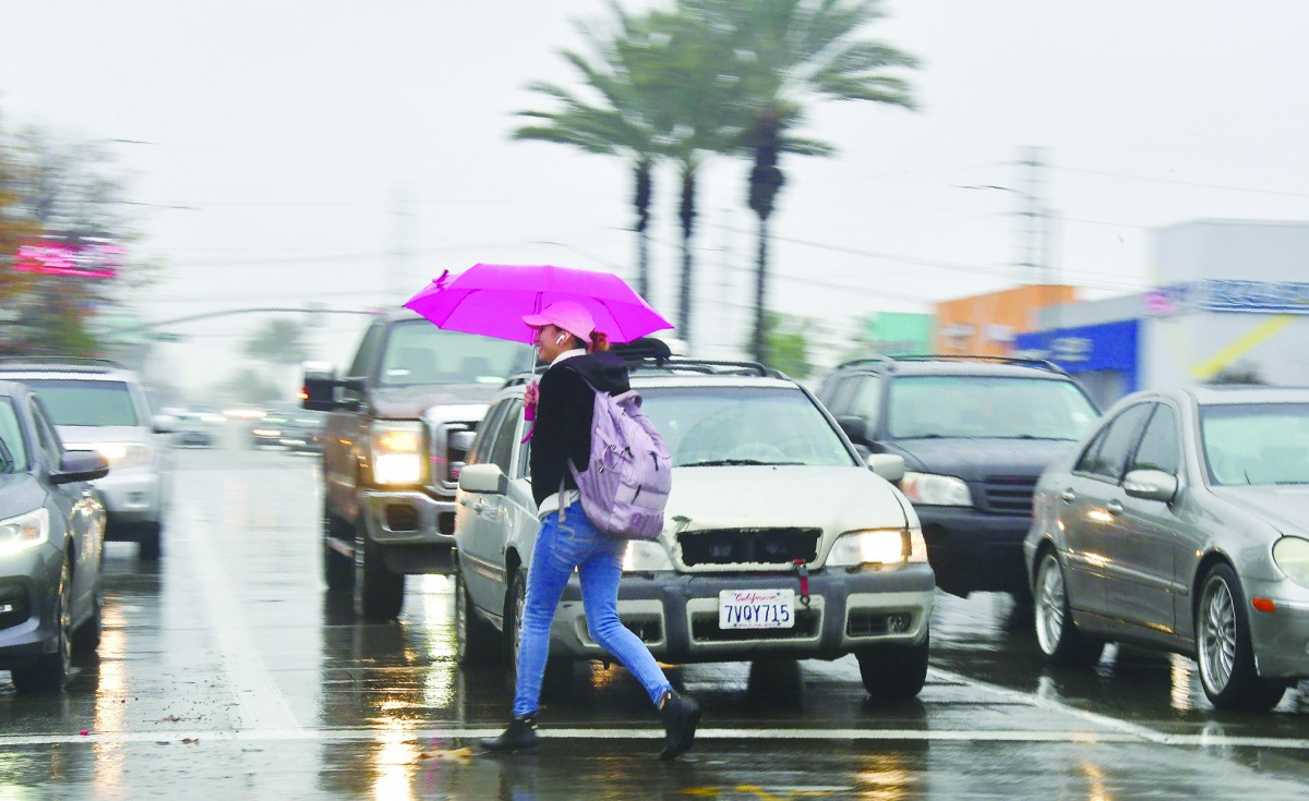 Pedestrian crosses a street in the rain in Montebello, California on January 16, 2019 as southern California is hit by another storm, pushed by an atmospheric river, with rainfall expected to get heavier later into the day.  AFP / Frederic J Brown

