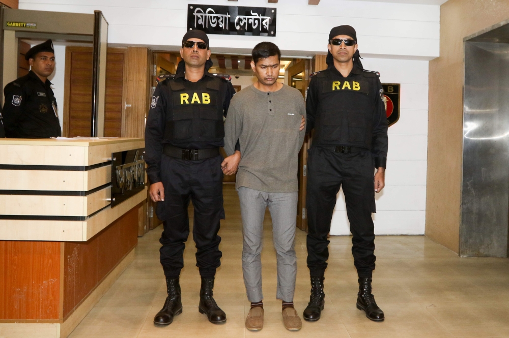 The Rapid Action Battalion (RAB) escort arrested suspected militant Mamunur Rashid (C) in Dhaka on January 20, 2019.  / AFP / STR