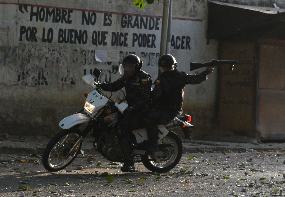 A riot policeman on a motorcycle points his gun during clashes with anti-government demonstrators in the neighborhood of Los Mecedores, in Caracas, on January 21, 2019. AFP / Federico Parra 
