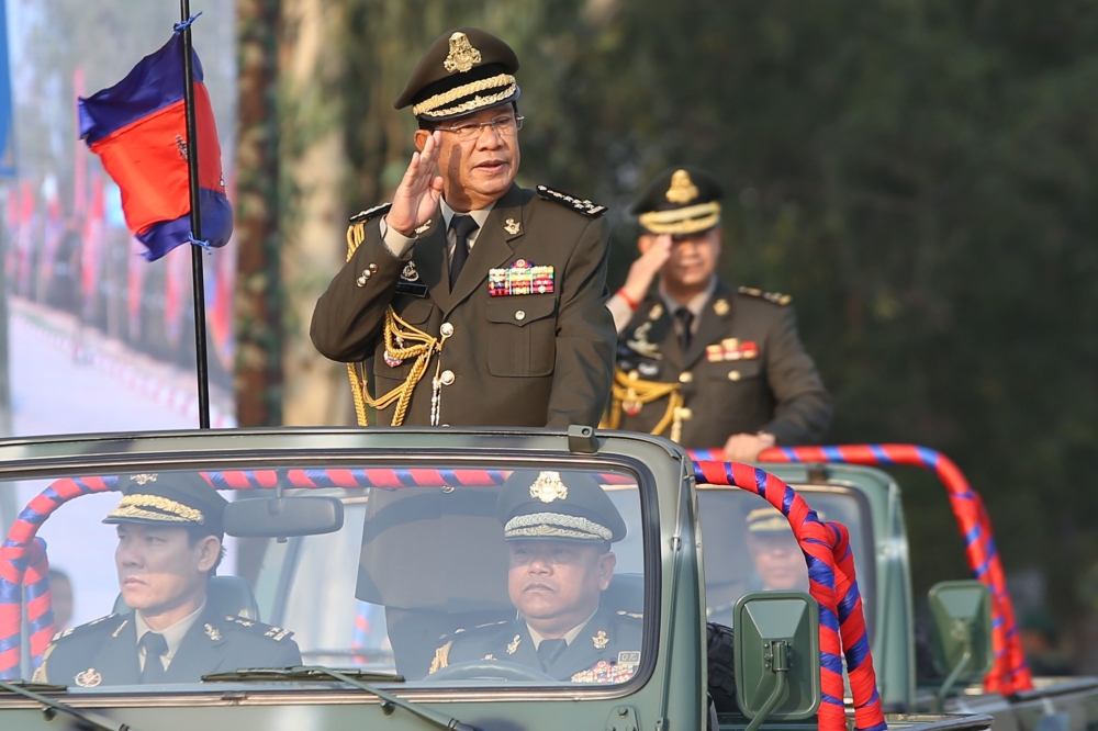 Cambodian Prime Minister Hun Sen (L) salutes accompanied by his son, Commander of Cambodian Infantry Army, Lieutenant General Hun Manet (R) during an inspection of troops at a ceremony marking the 20th anniversary of the formation of Cambodian Infantry Ar