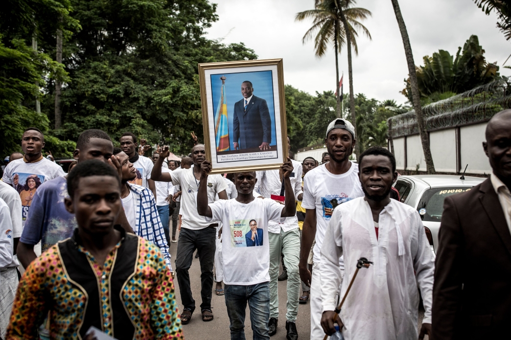 A Supporter of Democratic Republic of Congo new President shows a portrait of outgoing President Joseph Kabila, ahead of the Presidential Inauguration on January 24, 2018.  AFP / John WESSELS
