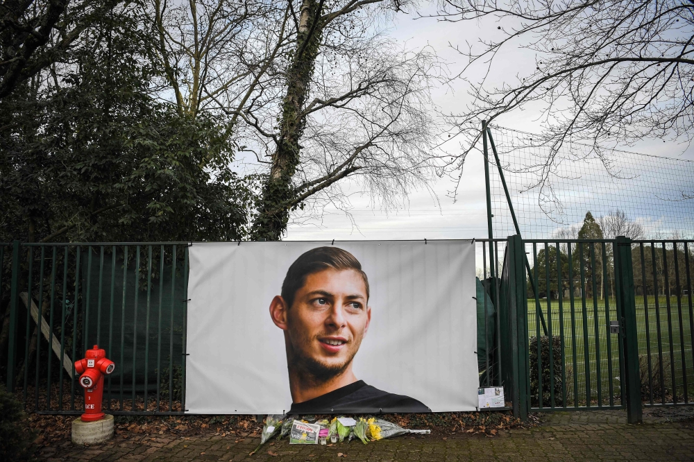 Flowers and candles are left with the front page of French sports daily newspaper 'L'Equipe' reading 