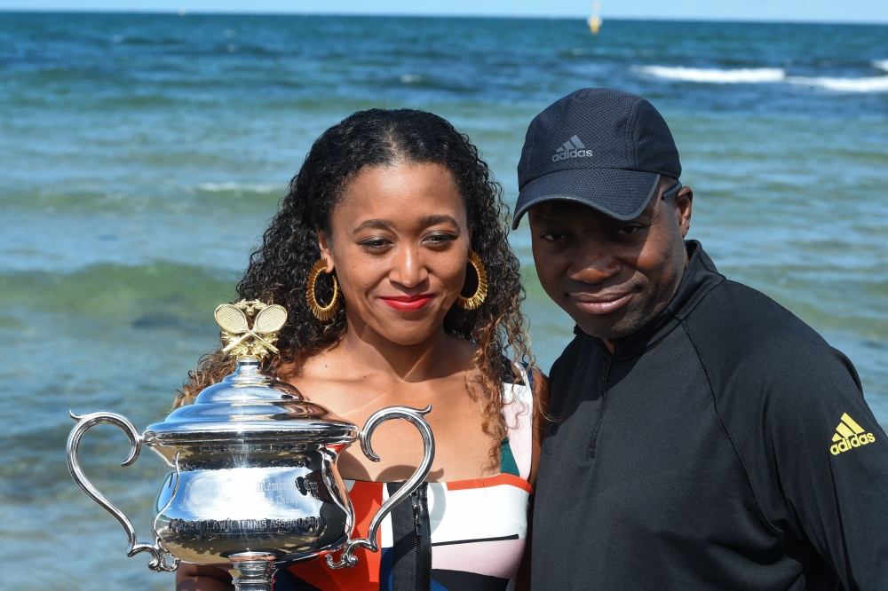 Japan's Naomi Osaka and her father Leonard Francois pose for photographs with the championship trophy at the Brighton Beach in Melbourne on January 27, 2019, a day after her victory against Czech Republic's Petra Kvitova in the women's singles final at th