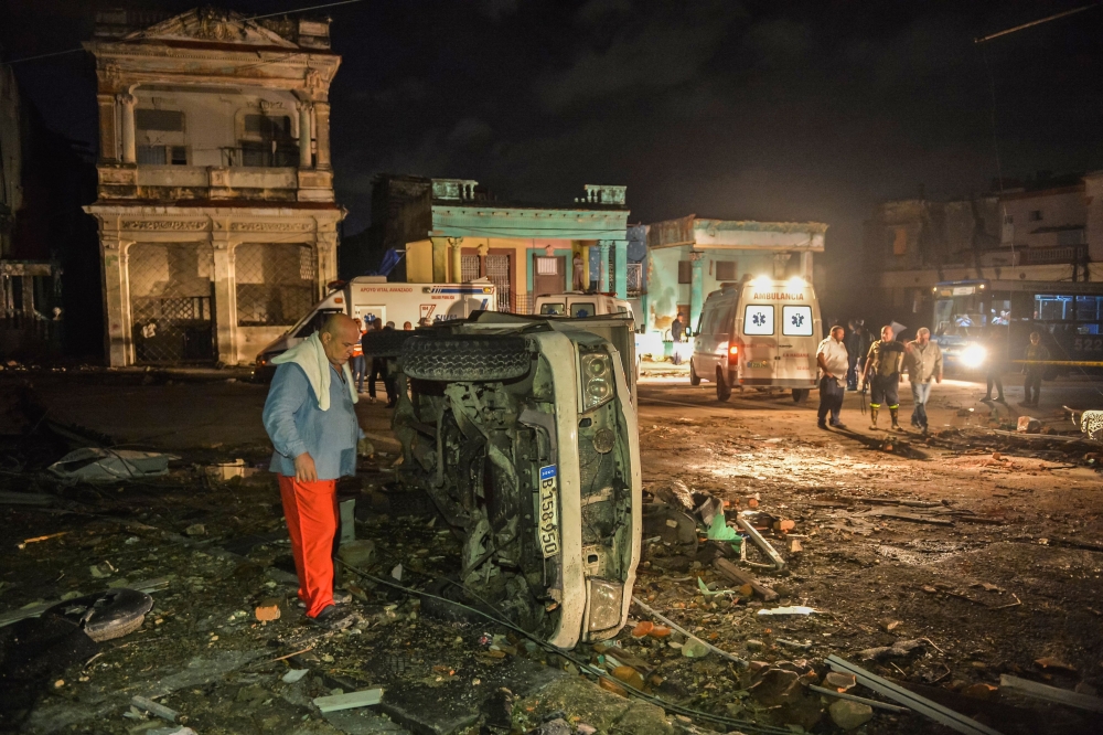 A man inspects a damaged car lying on its side in the tornado-hit Luyano neighborhood in Havana early on January 28, 2019. AFP / YAMIL LAGE