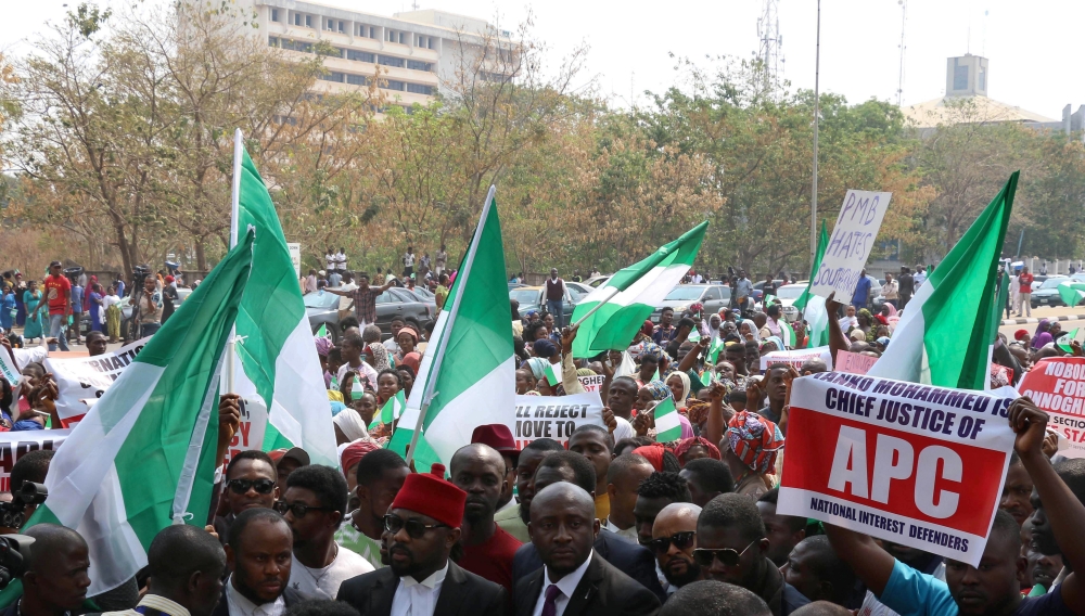 Nigerian lawyers and protesters, some holding up the national flag, gather outside the secretariat of the Nigerian Bar Association during a protest in Abuja over the suspension of Chief Justice of Nigeria (CJN) in Abuja on January 28, 2019. AFP / SODIQ AD