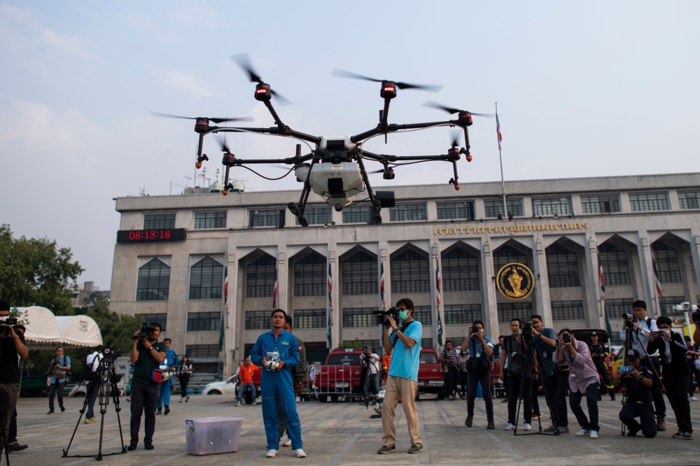 Bangkok Metropolitan Administration (BMA) officials watch a drone taking off fitted with a water tank during a demonstration to make artificial rain to tackle air pollution in Bangkok on January 31, 2019. AFP / Jewel SAMAD