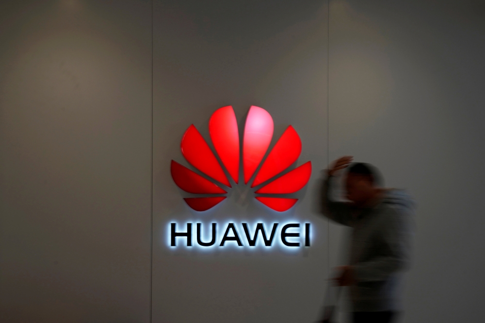 FILE PHOTO: A man walks by a Huawei logo at a shopping mall in Shanghai, China, Dec. 6, 2018. REUTERS/Aly Song/File Photo