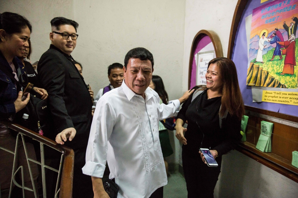 A Philippine President Rodrigo Duterte impersonator (C), who goes by the name Cresencio Extreme, and a North Korean leader Kim Jong Un impersonator (2nd L), who goes by the name Howard X, attend a church service in the Central district of Hong Kong on Feb