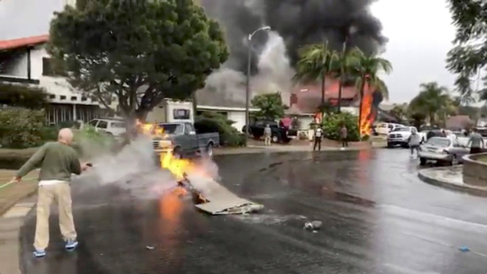 A man puts out fire on a piece of debris from a plane that crashed into a house in a residential neighborhood in Yorba Linda, California, U.S., February 3, 2019, in this still image from video obtained from social media. Joshua Nelson/via REUTERS
