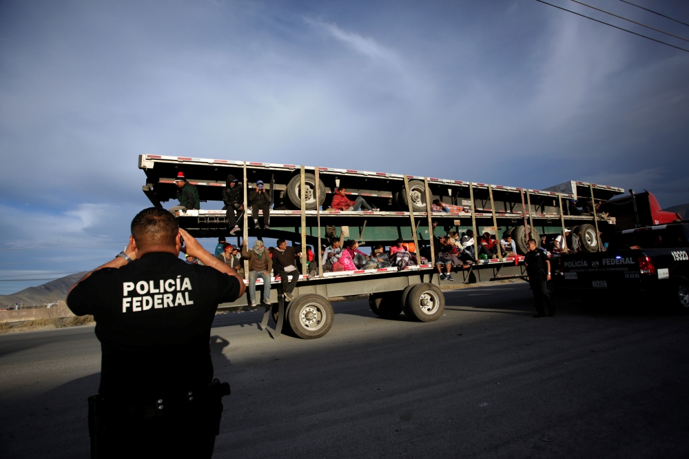 A police officer takes pictures of migrants as they arrive in the back of a truck to a provisional shelter during their journey towards the United States, in Saltillo, Mexico February 3, 2019. Reuters/Daniel Becerril
