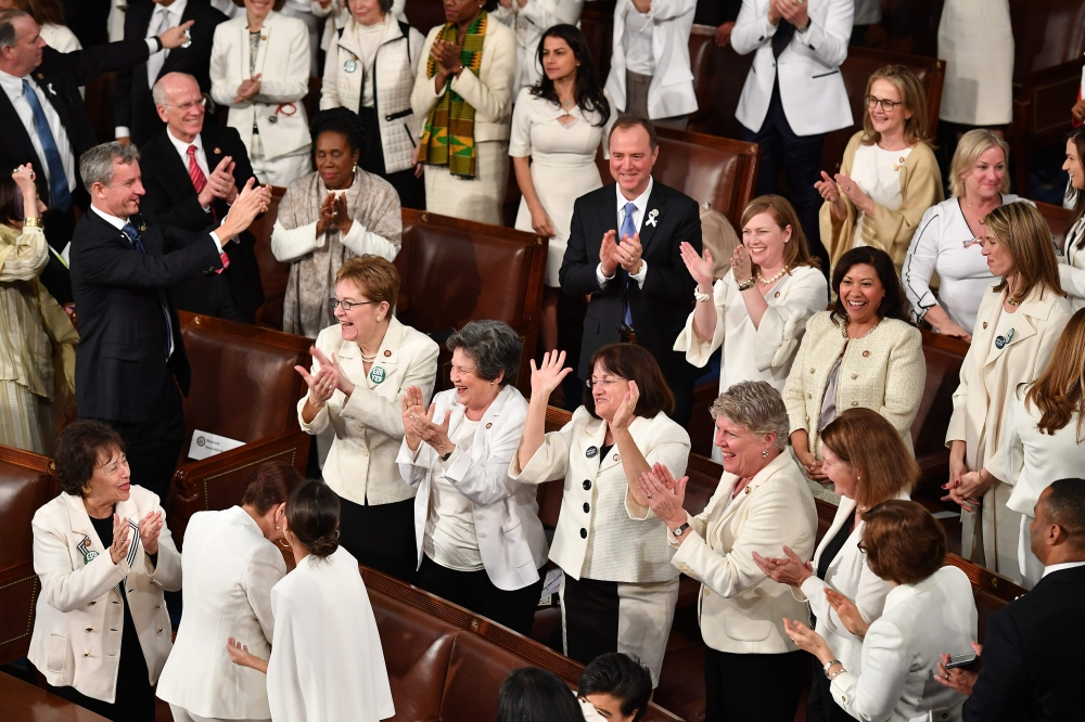 Congresswomen, dressed in white in tribute to the women's suffrage movement, applaud as they attend the State of the Union address at the US Capitol in Washington, DC, on February 5, 2019. / AFP / MANDEL NGAN