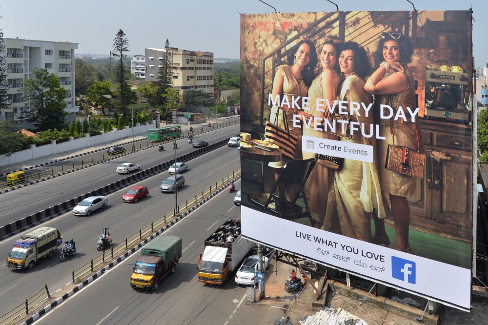 Indian commuters pass a poster advertising Facebook Live 'What You Love' campaign in Bangalore on March 22, 2018. AFP / Manjunath Kiran