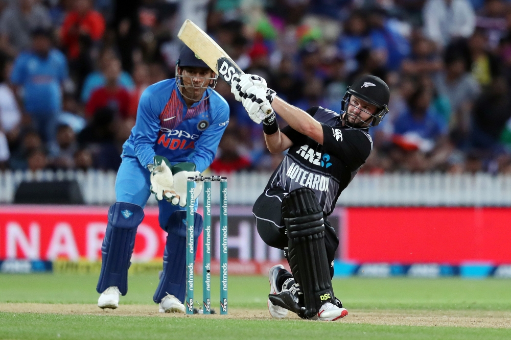 New Zealand's Colin Munro (R) plays a shot as India's MS Dhoni (L) looks on, during the third Twenty20 international cricket match between New Zealand and India in Hamilton on February 10, 2019. (AFP / MICHAEL BRADLEY)