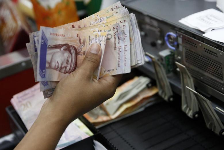 A cashier counts Venezuelan bolivar notes in a state-run supermarket in Caracas, January 9, 2015. Reuters/Carlos Garcia Rawlins