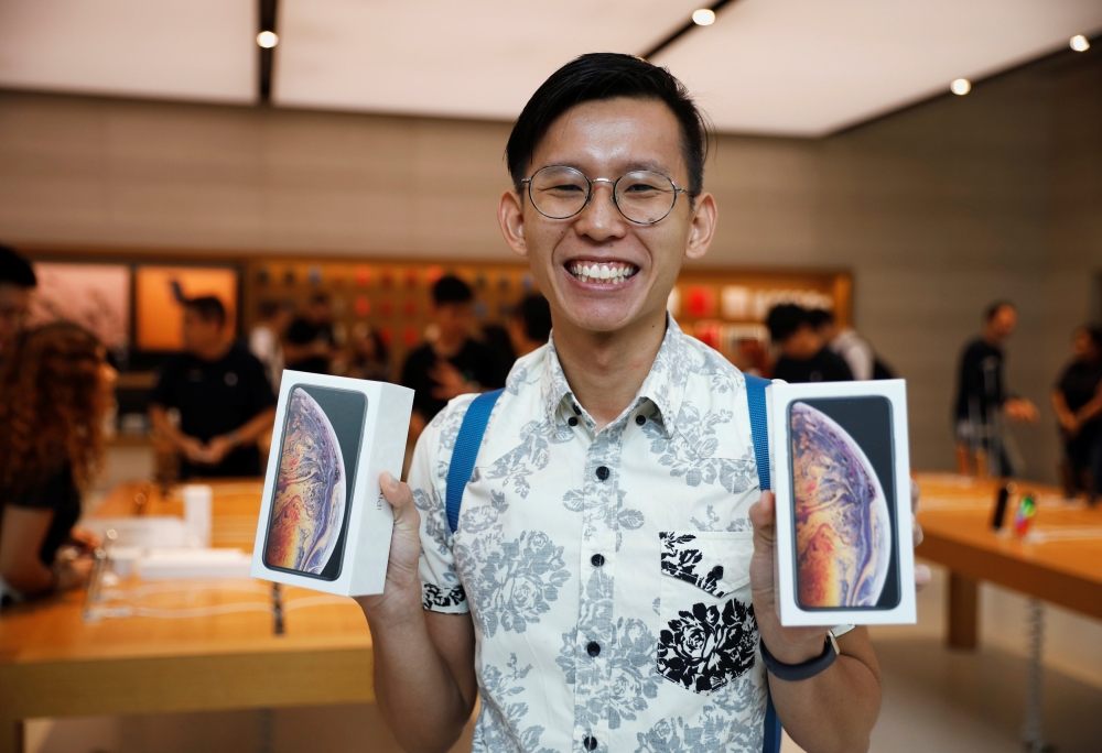 FILE PHOTO: Singaporean Daniel Lim, 23, the first in line to buy the newly released iPhones poses with his purchases at the Apple Store in Singapore, September 21, 2018. Reuters/Edgar Su