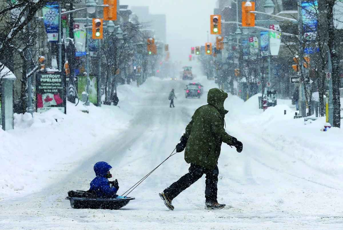 A man pulls a child in a sled during a winter snow storm in Ottawa, Ontario, Canada, February 13, 2019. Reuters/Chris Wattie