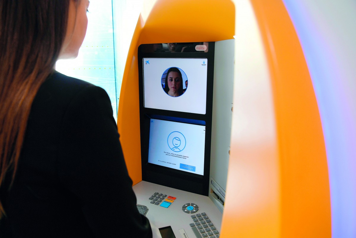 A woman uses an ATM with facial recognition technology during the presentation of the new service by CaixaBank in Barcelona on February 14, 2019. AFP / Lluis Gene 