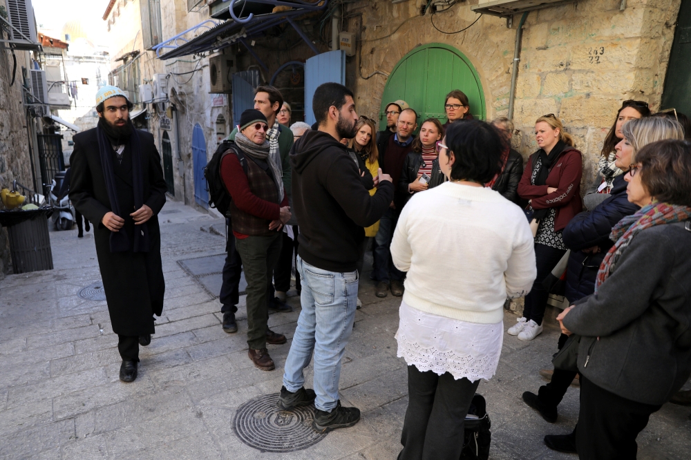 Tour guides, Noor Awad, a Palestinian from Bethlehem, and Lana Zilberman Soloway, a Jewish seminary student, speak to a group of tourists during the Dual Narrative tour they lead in Jerusalem's Old City February 4, 2019. Reuters/Ammar Awad
 