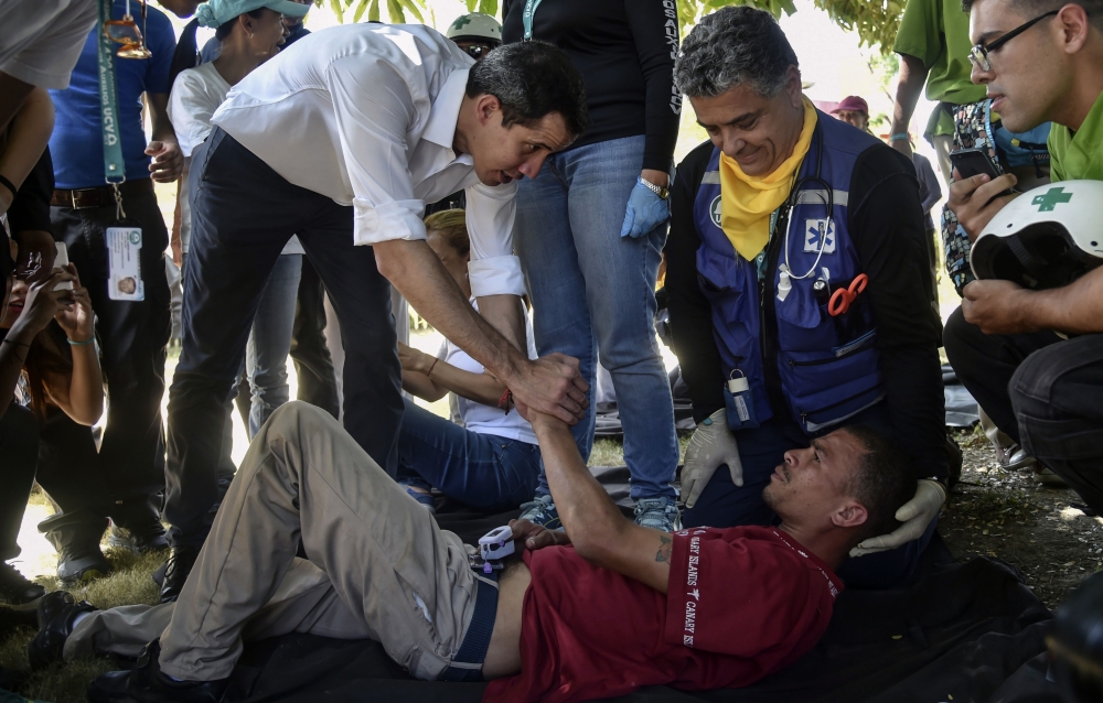 Venezuelan opposition leader and self-declared acting president Juan Guaido (L) greets volunteers of the movement 