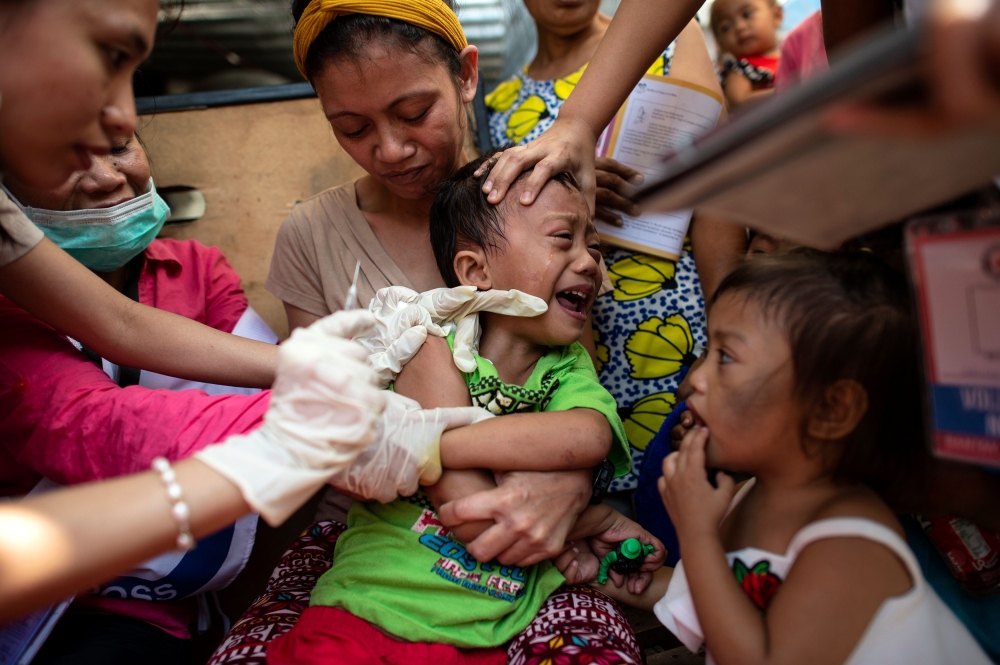 A child reacts during a Philippine Read Cross Measles Outbreak Vaccination Response in Baseco compound, a slum area in Manila on February 16, 2019.   AFP / Noel CELIS
