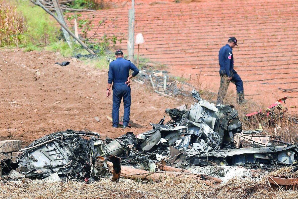Indian Air Force (IAF) personnel gather around the wreckage of one Surya Kiran 'Hawk' aircraft after two of them collided in mid-air and crashed during India's biennial international Air Show rehearsal at the Yelahanka Air Force Station in Bangalore on Fe