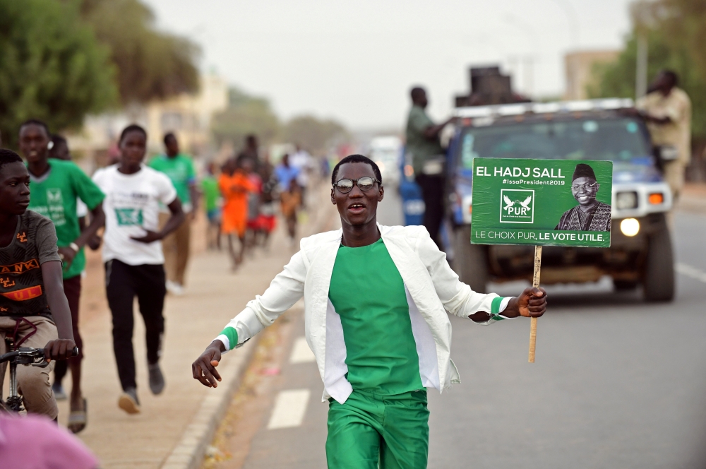 A supporter runs holding an election poster of the Party of Unity and Assembly (PUR) candidate Issa Sall during his campaign in Dahra Djoloff, Louga region, Senegal February 18, 2019.  Reuters/Sylvain Cherkaoui

 