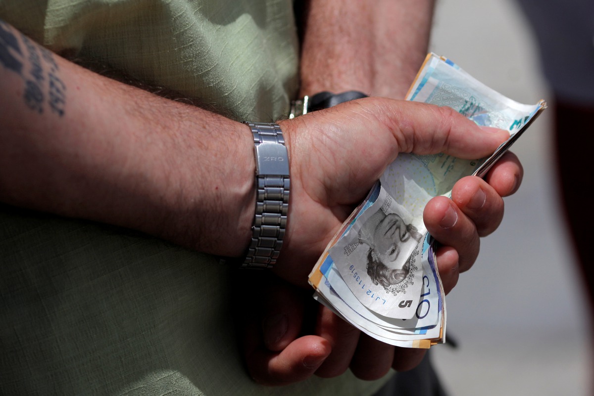 A man holds various English Pound notes as he waits in line to exchange it for Euros notes outside a money exchange office in the British overseas territory of Gibraltar. June 24, 2016 (AFP) 