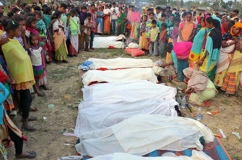 People stand next to the bodies of tea plantation workers, who died after consuming bootleg liquor, in Golaghat in the northeastern state of Assam, India, February 22, 2019. Reuters 