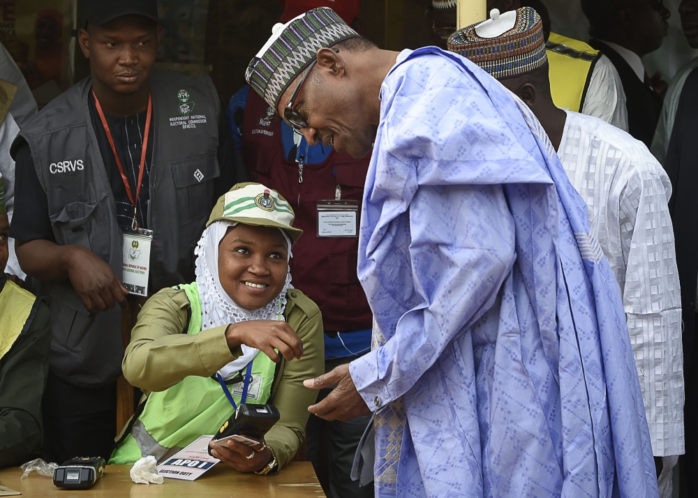 Candidate of the All Progressives Congress (APC) and incumbent President Muhammadu Buhari (R) verifies his card to vote at a polling station in his native hometown Daura in Katsina State, northwest Nigeria, on February 23, 2019. (AFP / PIUS UTOMI EKPEI)