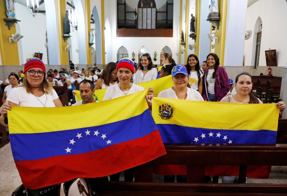 Supporters of Venezuelan opposition leader Juan Guaido, who many nations have recognized as the country's rightful interim ruler, hold Venezuelan flags during a meeting at the Queen of the Most Holy Rosary Cathedral in Willemstad on the island of Curacao,