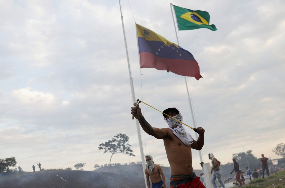 A protester uses a slingshot during clashes with Venezuelan soldiers along the border between Venezuela and Brazil in Pacaraima, Brazil February 23, 2019. REUTERS/Ricardo Moraes 