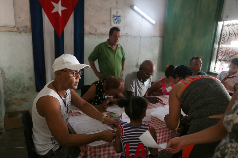 Election officials check the documents of a voter at a polling station during a constitutional referendum in Havana, Cuba, February 24, 2019. Reuters/Fernando Medina