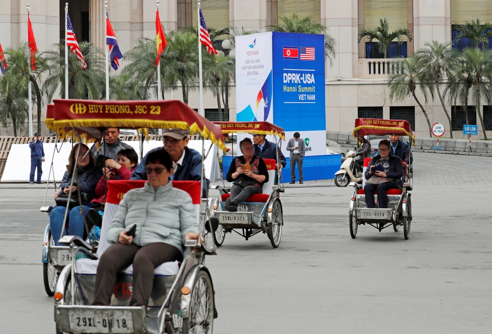 Rickshaws transport tourists next to a sign for the upcoming North Korea-U.S. summit, near the Metropole hotel in Hanoi, Vietnam, February 25, 2019. REUTERS/Kim Kyung-Hoon