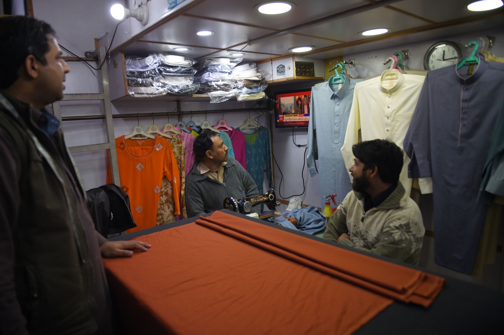 Pakistani tailors watch a television broadcasting breaking news in Islamabad on February 27, 2019. AFP / FAROOQ NAEEM
 