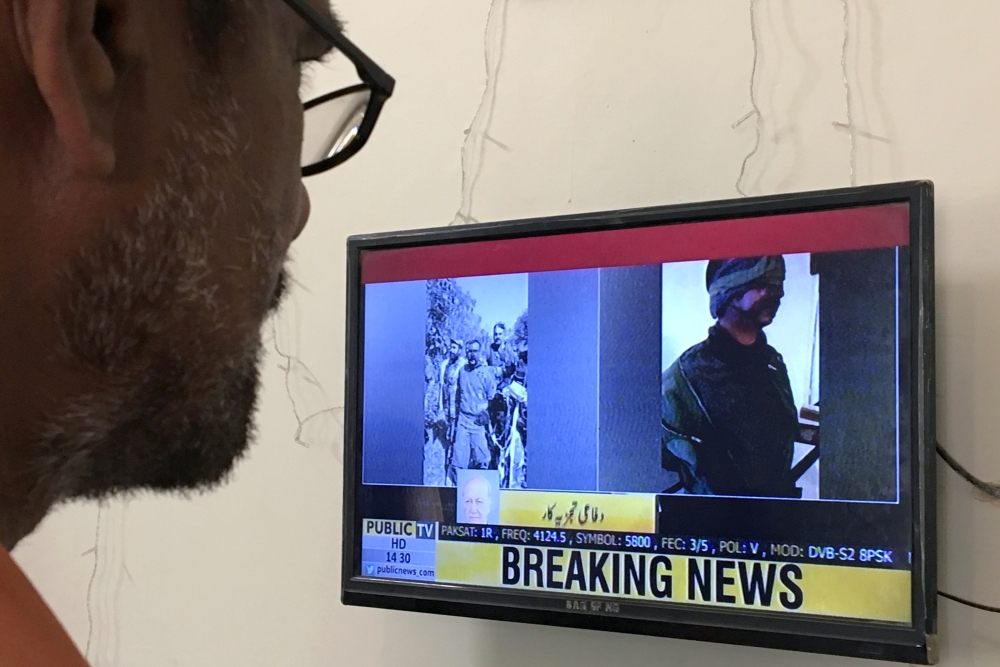 A man looks at a television screen displaying the pictures of the Indian pilots, said to be captured by Pakistan after shooting down two Indian planes, in Karachi, Pakistan February 27, 2019. Reuters/Akhtar Soomro