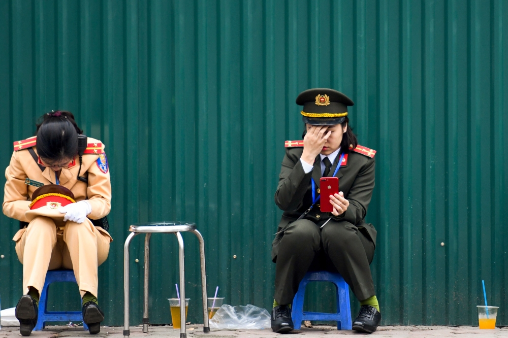 Two Vietnamese policewomen rest near the Melia hotel following the second US-North Korea summit in Hanoi on February 28, 2019. AFP / Ye Aung Thu
 