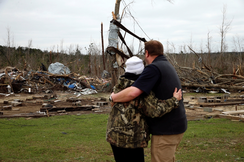 A man hugs Julie Morrison while looking at the remains of her home following a string of tornadoes that resulted in several fatalities in Beauregard, Alabama, U.S., March 4, 2019. REUTERS/Elijah Nouvelage