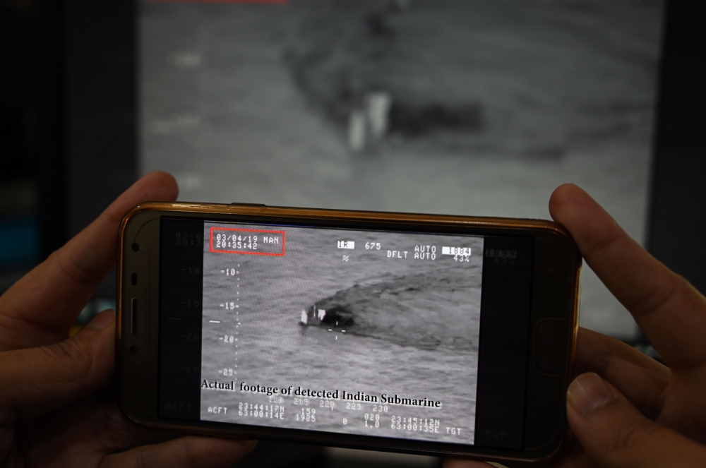 A Pakistani journalist watches a video released by Pakistan's Navy that allegedly shows an Indian submarine, on a smartphone in Islamabad on March 5, 2019. AFP / AAMIR QURESHI