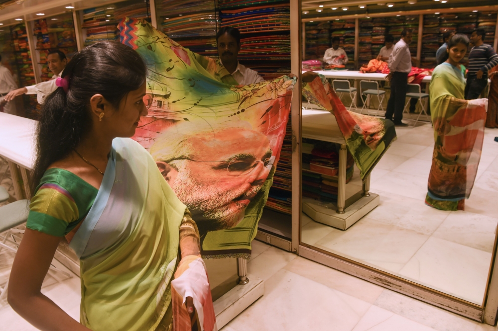 A saleswoman tries on a saree bearing the image of Indian Prime Minister Narendra Modi to show it to customer at a shop in Mumbai on February 19, 2019. AFP / Indranil Mukherjee
 
 